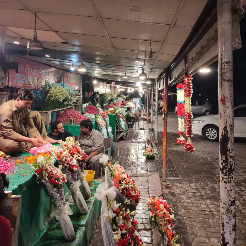 Florists selling flower garlands and bouquets from stalls along a covered street at night