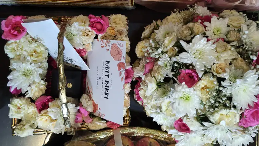 Floral gift baskets of roses and white flowers with a printed wedding invitation card