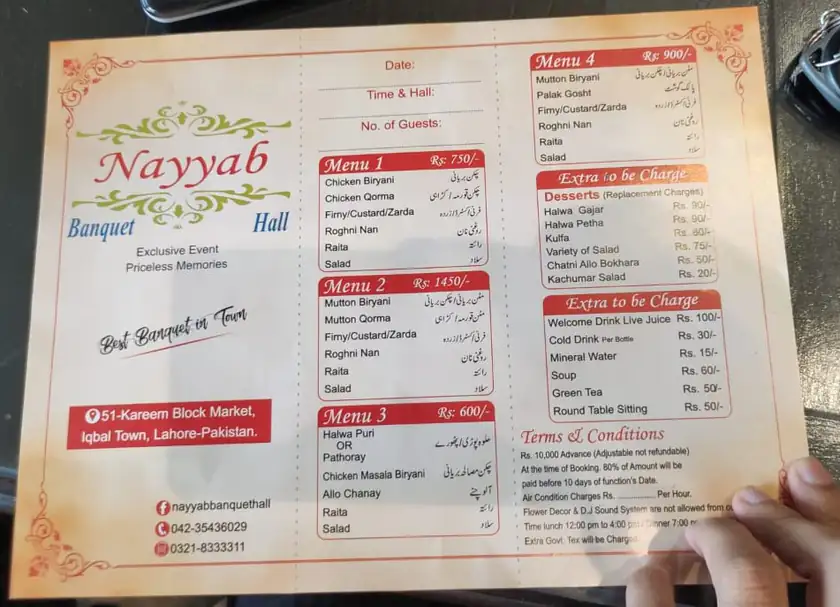 A hand holding a banquet hall’s printed menu and price sheet, listing Menu 1 to Menu 4 with prices and terms and conditions