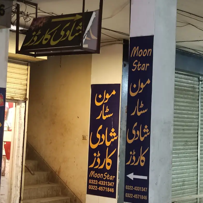 Wedding card shops with Urdu signboards advertising wedding card printing and listing phone numbers