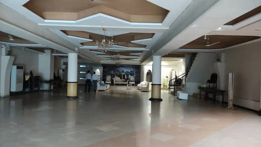 Wedding hall lobby in Faisal Town with a decorated ceiling and pillars, and a few people standing at the far end